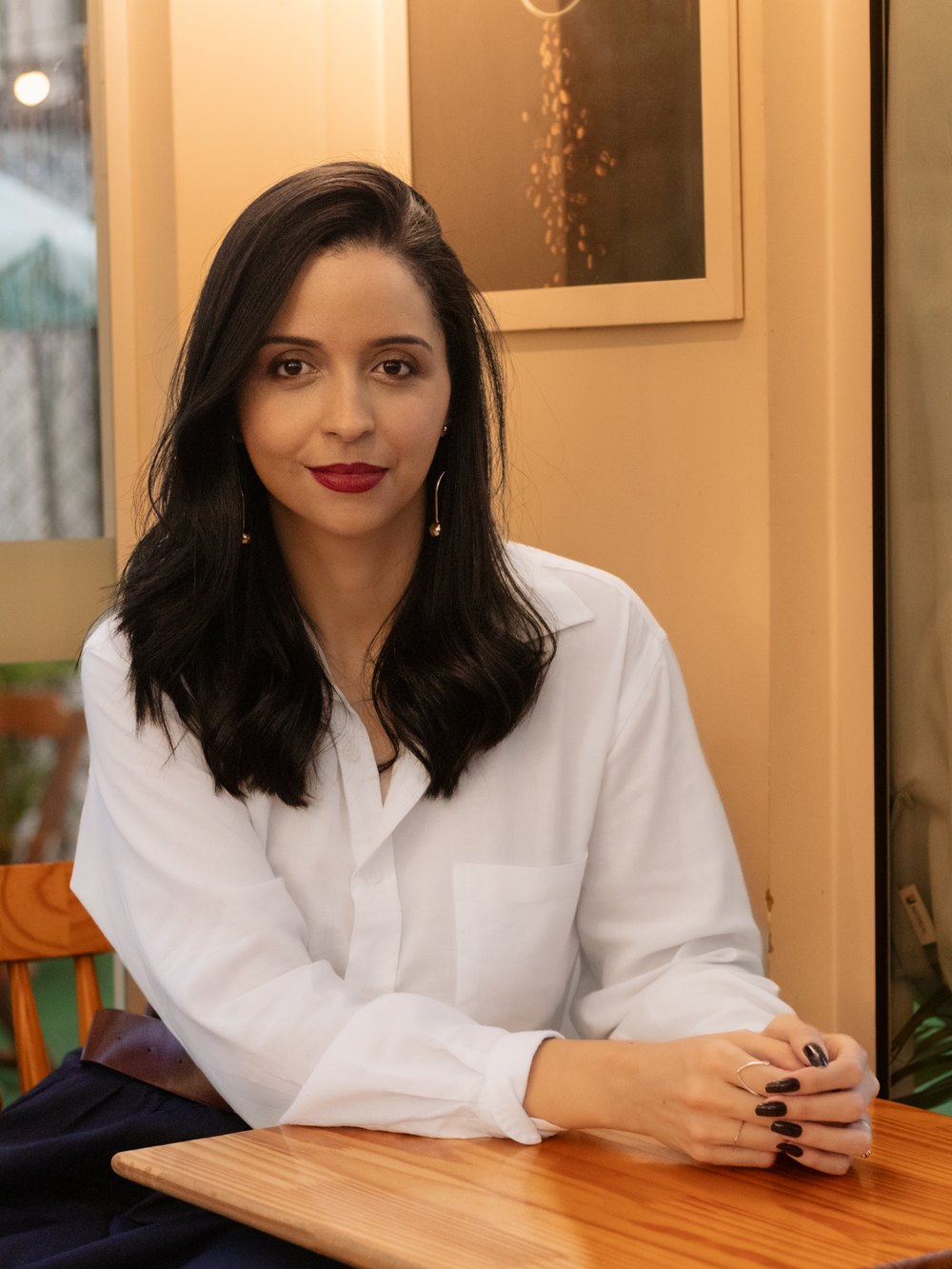 Jessica Araujo sentada em uma mesa, pronta para conversar